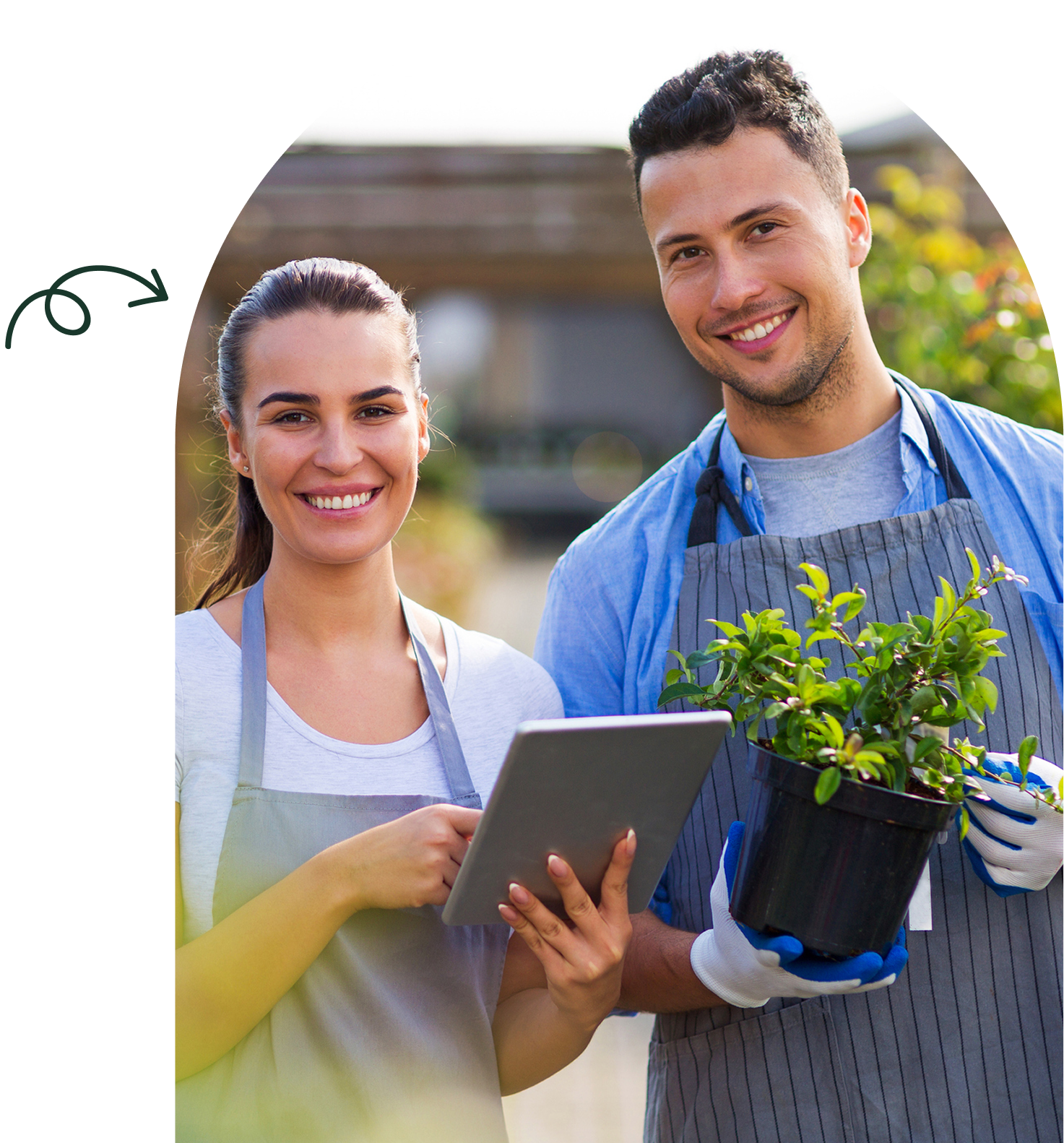 Two gardeners smiling, holding plant and tablet.